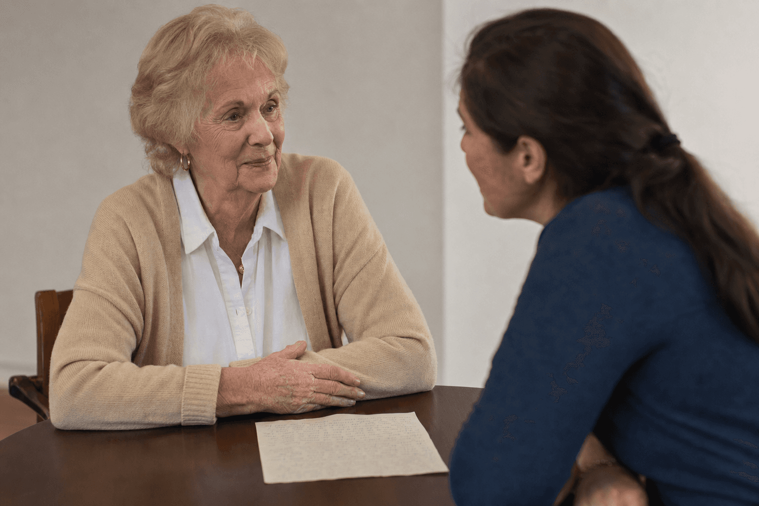 A donor and nonprofit staff member in warm conversation about legacy giving, with a handwritten letter on the table