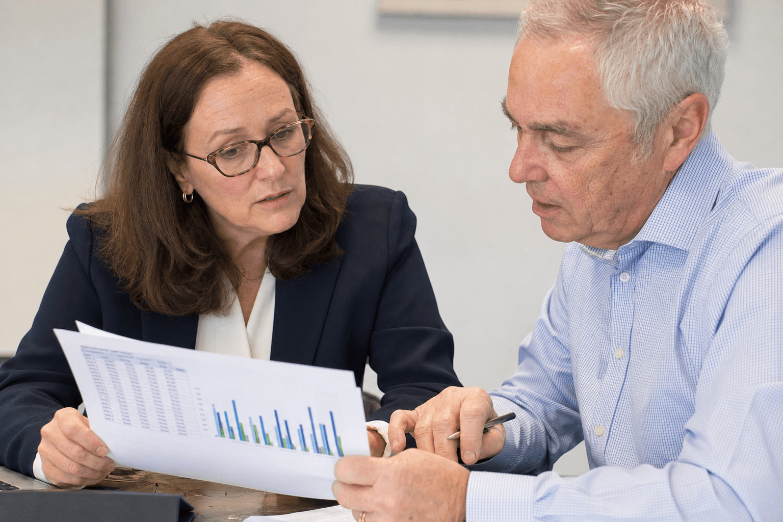 A board member and fundraising consultant reviewing a capital campaign budget and financial charts